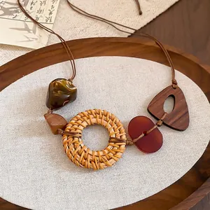 Bohemian rattan hoop and resin triangle pendant necklace on a rustic wooden tray