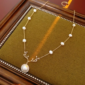 Dettaglio della collana corno dorata con perle e zirconi su vassoio in velluto