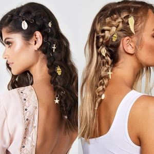 Detailed view of golden braid charms like shells and leaves on braided hair