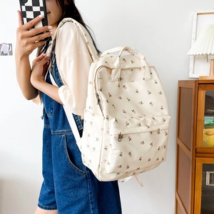 Detailed side view of beige floral canvas backpack with pink flowers and metal zipper