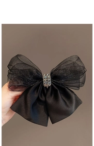 Detail of black mesh bow hair clip with sparkling rhinestone center and satin fabric