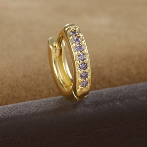Macro shot of gold hoop earrings with vertical purple zircon inlays and prong setting