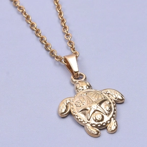 Macro detail of golden turtle pendant with starfish and shell carvings on purple fabric