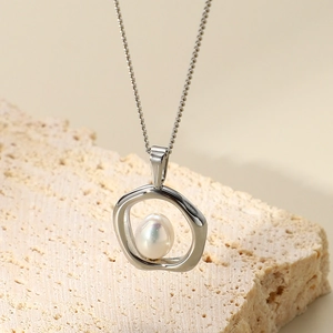 Irregular silver ring necklace with white pearl pendant on minimalist stone stand