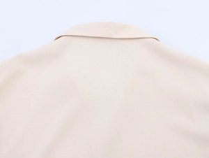 Detail view of beige linen blouse featuring coconut tree embroidery on the back neck area