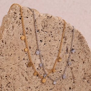 Detail of silver and gold daisy pendant necklaces on natural stone background