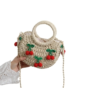 Handgefertigte Strohtasche mit gehäkelten Kirschen und Ringgriffen für den Strand