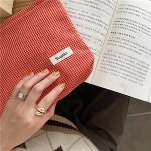 Detalle de un neceser de jacquard con estampado de pata de gallo rojo y blanco en la mano