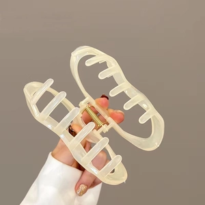 Detailed view of a creamy translucent cloud hair claw clip held in hand for size