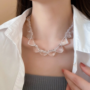 Close-up of a clear acrylic heart-shaped beaded necklace on a female neck and collarbone