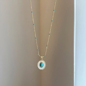 Détail d'un collier vintage doré avec pendentif en turquoise et incrustation de nacre