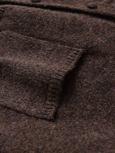 Macro detail of dark brown knit sweater showing ribbed pocket and fuzzy wool texture
