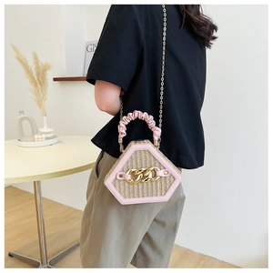 Pink woven straw hexagon handbag with decorative chunky gold chain and ruffled handle