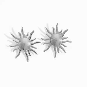 Close-up of silver sun-shaped stud earrings with wavy rays and polished metal finish
