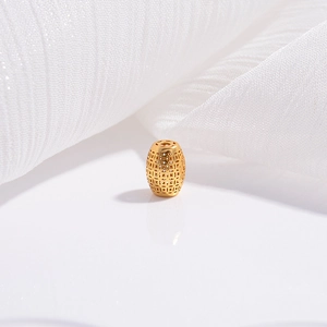 Macro shot of gold hollow cylinder spacer bead with intricate geometric mesh patterns