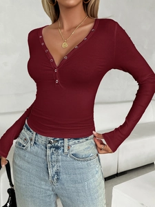 Detail of burgundy ribbed knit top featuring a deep V-neck and metal snap buttons