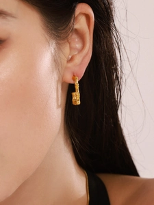 Close-up of a model wearing golden bamboo texture U-shaped hoop earrings in a modern style