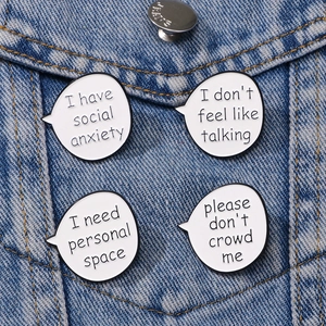 Set of four white enamel quote pins with social anxiety text on blue denim jacket