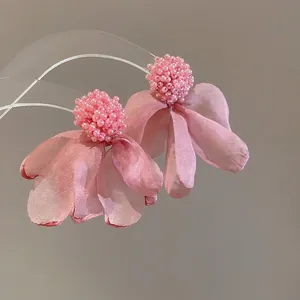 Pink cluster flower petal earrings with beaded detail on minimalist acrylic stand