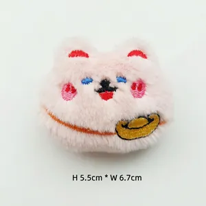 Detail showing the 5.5x6.7cm pink plush cat pendant with gold ingot embroidery details