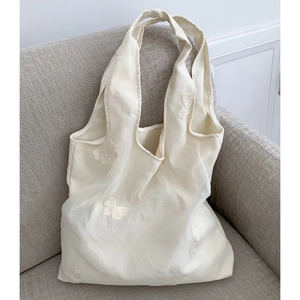 Detail of floral butterfly embroidery on creamy white layered tulle shoulder bag