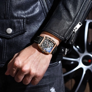 Men's skeleton quartz watch with golden tonneau case and black leather strap on wrist