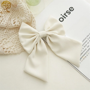 Detail of elegant cream fabric bow hair clip with long ribbons in a French style