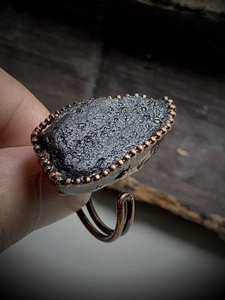 Macro shot of a raw black meteorite stone set in a vintage bronze beaded edge ring base