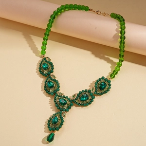 Close-up of vintage necklace with green teardrop crystal pendant and beaded chain detail
