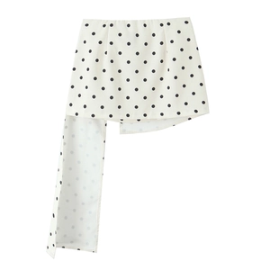 Détail d'une jupe mi-longue irrégulière blanche à pois noirs avec un long ruban décoratif