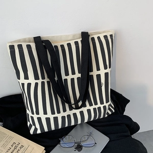 Detail of minimalist black and white striped canvas tote bag with tablet and daily items