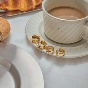 Set of four gold star earrings with zircon stones placed on a white coffee saucer