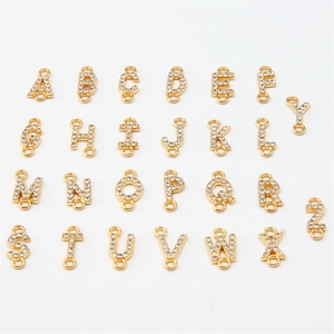 Set of 26 golden alphabet charms with clear rhinestones on white background