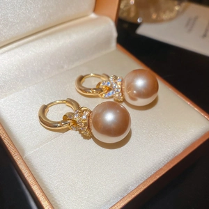 Gros plan de boucles d'oreilles perles champagne élégantes avec détail de nœud en zircon