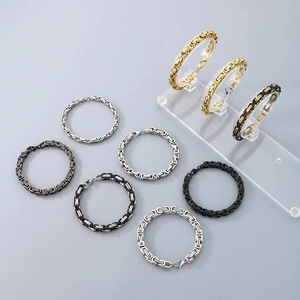 Titanium steel Byzantine chain bracelets in gold, silver, and black on a display stand