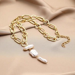 Close-up of Baroque pearl necklace with chunky gold chain on champagne silk fabric