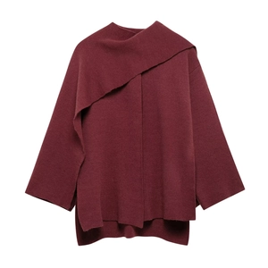 Macro view of the deep red knitted fabric and asymmetric closure detail of the coat