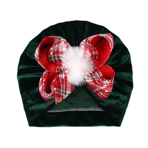 Detail of dark green velvet baby turban with red plaid bow and fluffy white pompom