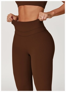 Detail of high-waist yoga pants showing elastic stretching effect on dark brown fabric