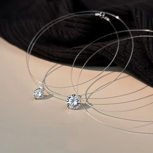 Macro di due ciondoli tondi in zirconia cubica su fili di nylon invisibili trasparenti
