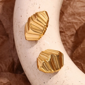 Détail de boucles d'oreilles en acier doré 18 carats avec motifs géométriques texturés