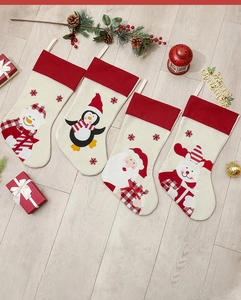 Set of four Christmas stockings featuring Santa, snowman, and reindeer on wood floor