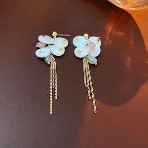 Detail of gold-plated flower earrings with colorful gemstones and hanging tassels