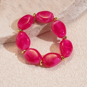 Macro detail of irregular rose red resin beads with white marble texture and gold accents