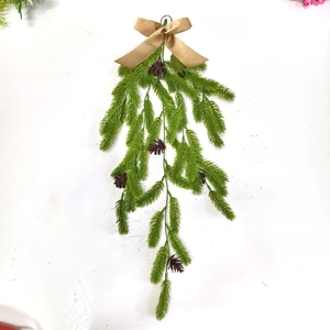 Close-up of artificial pine needles with pine cones and golden bow for Christmas decor