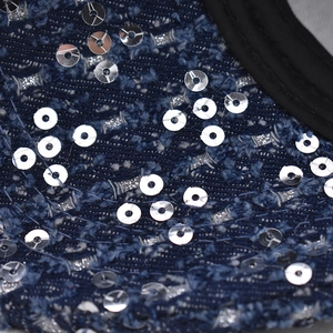 Close-up of sparkling silver sequins on blue denim baseball cap fabric with black piping