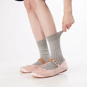 Rosa Satin-Ballerinas mit Schleife und Logo-Band, kombiniert mit grauen Strick-Socken
