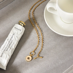 Detailansicht einer goldfarbenen Edelstahlkette mit Anhänger aus Muschel und Kristallen