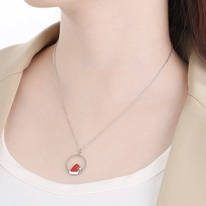 Detailed close-up of a silver necklace with a red and white Christmas hat pendant on a model