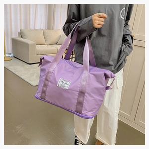 Detail of purple waterproof nylon travel bag with reinforced handles and brand tag